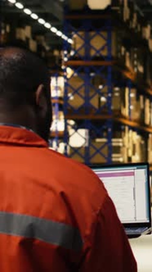 Vertical Video African American Male Employee Handling Parcel Logistics on Laptop