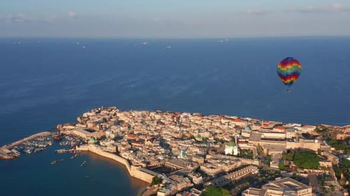Hot air balloon passing over Acre old city port houses and Mosque at sunrise, Aerial view