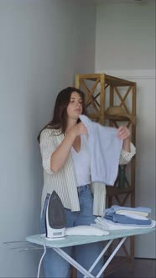 Woman Ironing Clothes on Ironing Board at Home