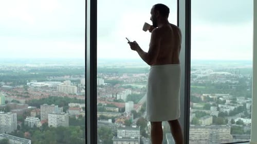 Man in Towel Uses Phone in Apartment