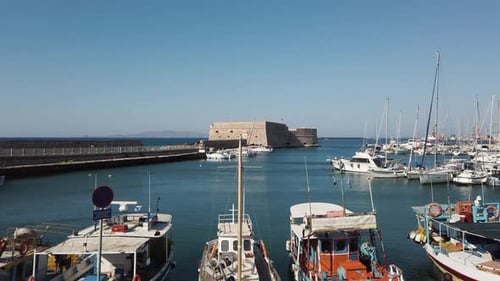 Fortress in Crete, Greece with little boats docked and a clear blue sky