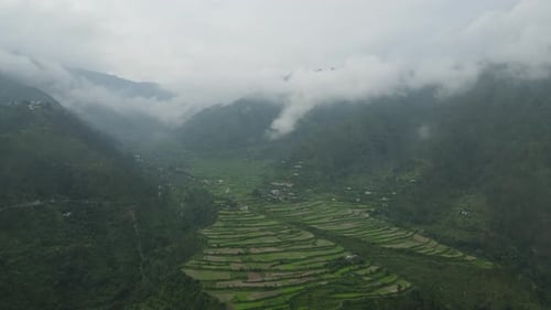 Luftaufnahme eines kleinen Dorfes in den Bergen, bedeckt mit Wolken.