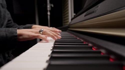 Close-up of a woman's hands in silver rings playing beautiful lyrical melody on the piano keys