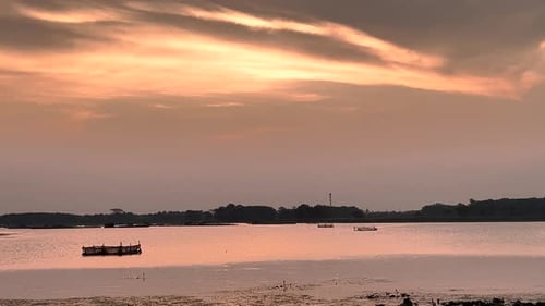 The golden sun dips below the horizon, casting a warm glow over the serene sunset lake.