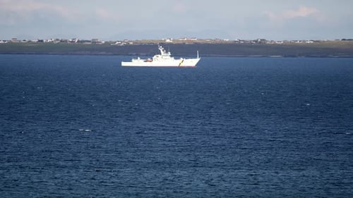 Telephoto shot of a Royal Navy fisheries patrol ship driving through rough seas into the inlet of Br