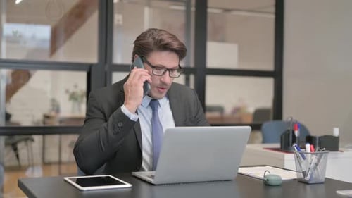 Businessman Talking on Phone at Desk in Office