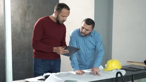 Zwei Architekten analysieren gemeinsam Baupläne für ein neues Innenraumprojekt