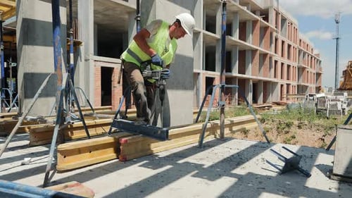 Ouvrier du bâtiment en train de forer sur un chantier de construction Un ouvrier du bâtiment est vu en train de forer dans un béton
