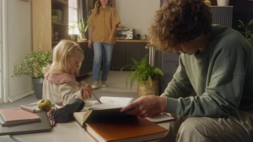 Child Drawing Doodles in Notebook While Brother Doing Homework