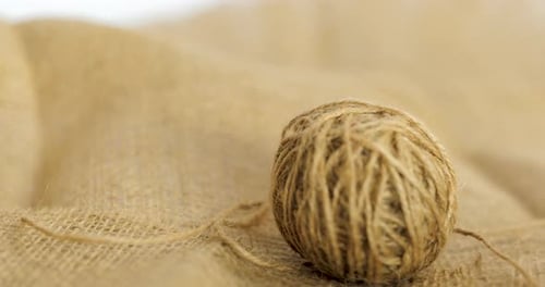 A Ball Of Jute Dropping Onto A Burlap Hessian Sack, Natural Fibre Textile Used As Twine