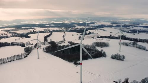 Fly Over Wind Turbines and Wind Mills in the Winter Field at Sunlight