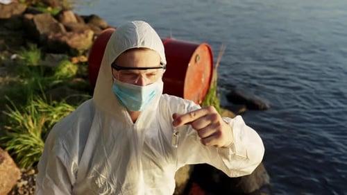 Water Analyst Examining Sample near Red Barrel