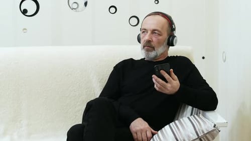 Man Using Smartphone and Listening to Music at Home