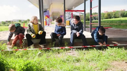 Children Sitting on Wall Near Playground on Sunny Day