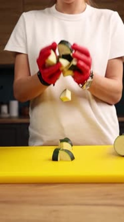 Person Juggling Chopped Zucchini in Bright Kitchen