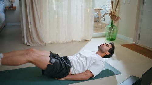 Man Lying on Yoga Mat Doing Leg Raises