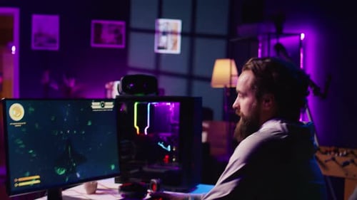 Mann schaltet den Computer ein, um Videospiele zu spielen, nachdem er in einer neonbeleuchteten Wohnung zu Hause angekommen ist