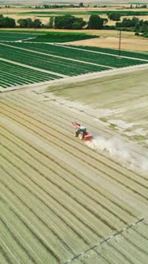 Verticle Tractor Working in a Field Surrounded by Farmlands - Aerial View