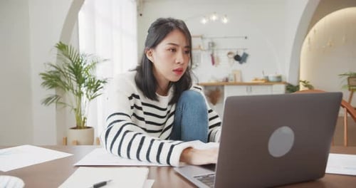 Woman Frustrated Working with Laptop and Papers at Home