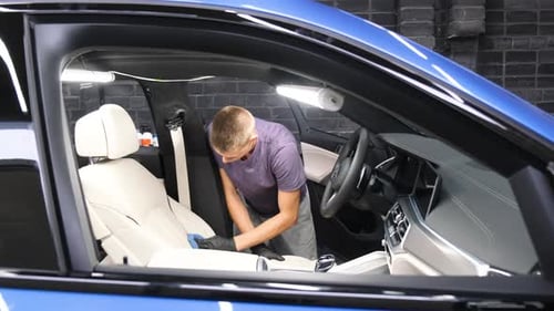 A Car Wash Worker Applies Detergent to a Car Seat