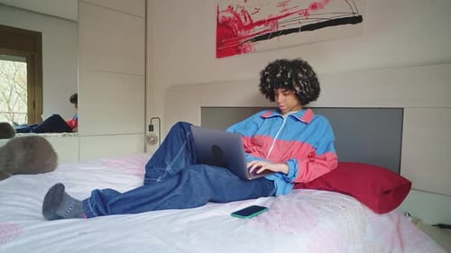 Junger Student arbeitet am Laptop im Bett