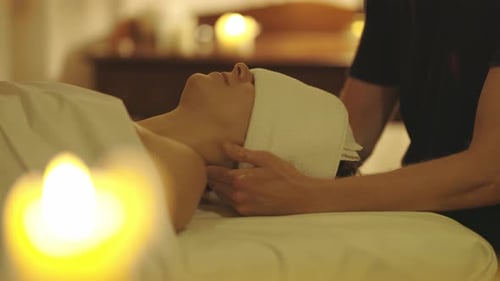 Eine entspannte Frau mit einem Handtuch über den Augen wird in einem Spa-Salon massiert