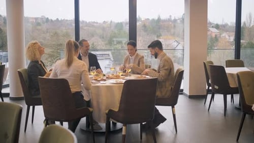 Smiling coworkers in restaurant talking during business lunch.