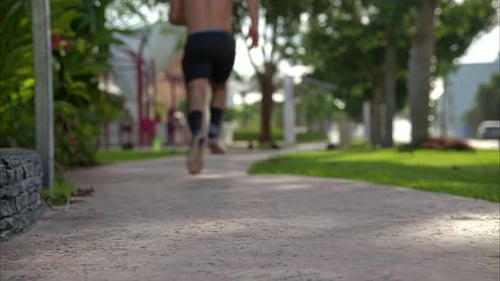 Man Running Shirtless in Park on Sunny Day