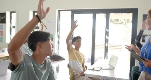 In high school, students raising hands in classroom, participating in discussion
