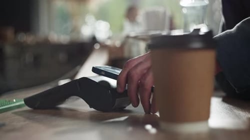 Closeup of a Man Paying for Coffee By Phone in a Cafe