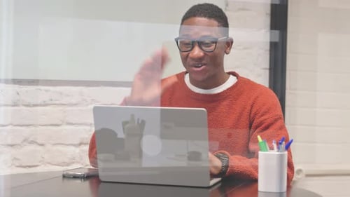 Young Man Video Calling on Laptop at Desk