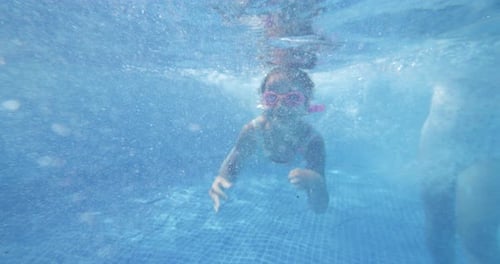 Under Water Shot: Female Kid with Goggles in a Swimming Pool, Swimming Towards the Ca