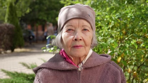 Portrait of an Elderly Grandmother with Gray Hair in a Hat in the Park in Autumn