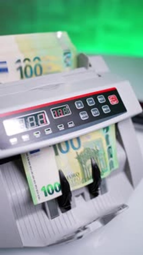 Money stack placed into cash counting machine. One hundred euro bills in a bank device.