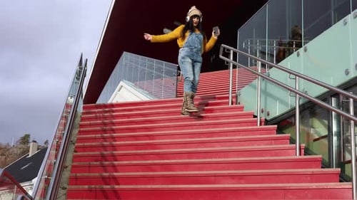 Cheerful Woman Dances on Steps with Headphones