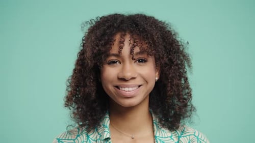 Smiling Woman Winking on Turquoise Background
