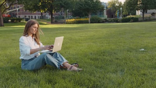 Woman Working on Laptop in Park on Lawn