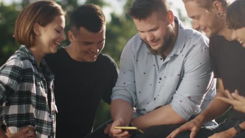 Young Adults Gathered Around Smartphone Outdoors