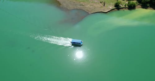 A Motor Boat with a Canopy Floats on a Lake with Clear Water