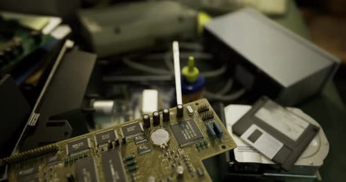 Old Circuit Board and Various Electronic Components Scattered on a Worktable