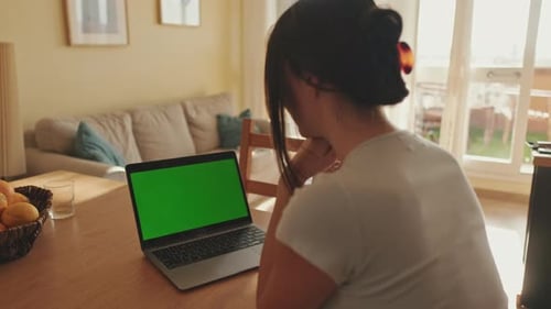 Young woman uses laptop green screen chroma key while sitting in apartme