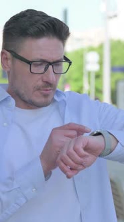 Man Uses Smartwatch in Urban Setting