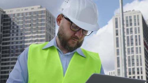 Professional Male Engineer in Hard Hat Using Laptop at Construction Site