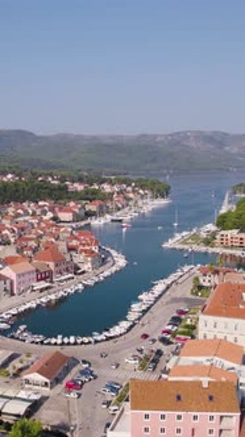 Stari Grad harbor on Hvar Island, Croatia, featuring boats, buildings, and mountains in aerial view