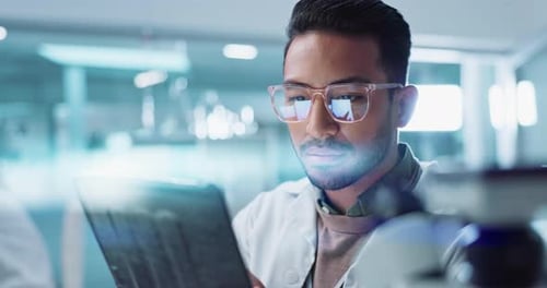 Scientist Smiling While Looking at Tablet in Lab