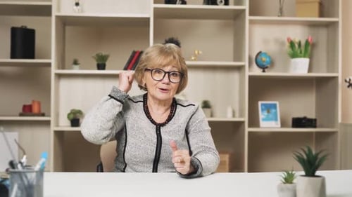 une vieille femme charismatique mène une conversation en ligne tout en faisant des gestes avec ses mains
