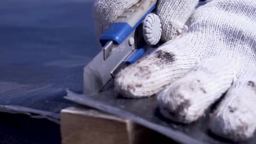 Construction Worker Cutting Roofing Felt with Utility Knife