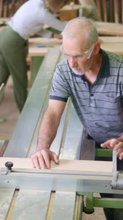 Senior Carpenter Cutting Wood on Sliding Table Saw