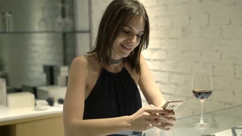 Young, Elegant Woman Texting On Smartphone Sitting In Cafe At Night