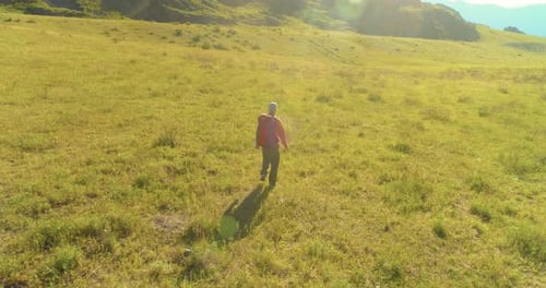 Flight Over Backpack Hiking Tourist Walking Across Green Mountain Field Huge Rural Valley at Summer